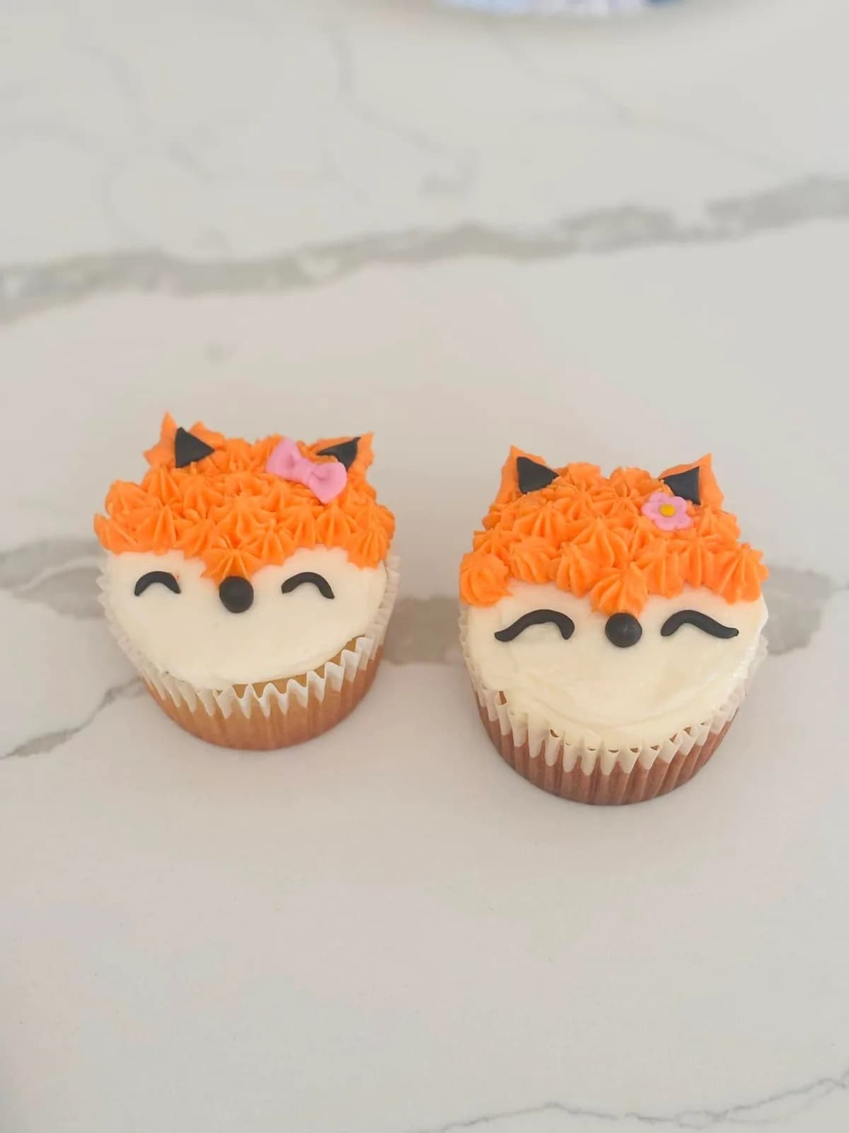 Two orange and white fox cupcakes made in a decorating class