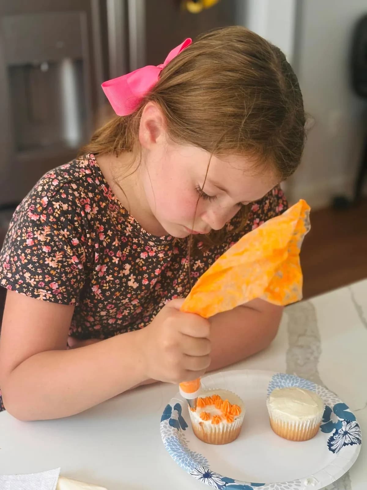 A participant learning to pipe frosting onto cupcakes in a Sweet Cake Factory class