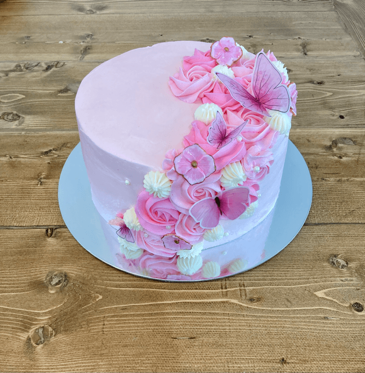 Pink celebration cake decorated with buttercream roses, flowers and pink butterflies